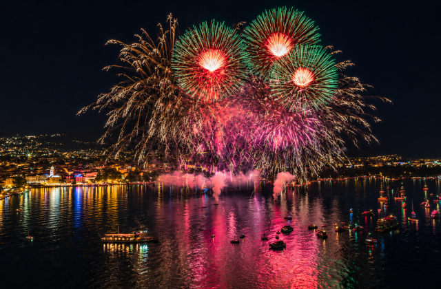 Spettacolo pirotecnico di Ferragosto sul Lago di Garda con riflessi colorati sull acqua e barche illuminate