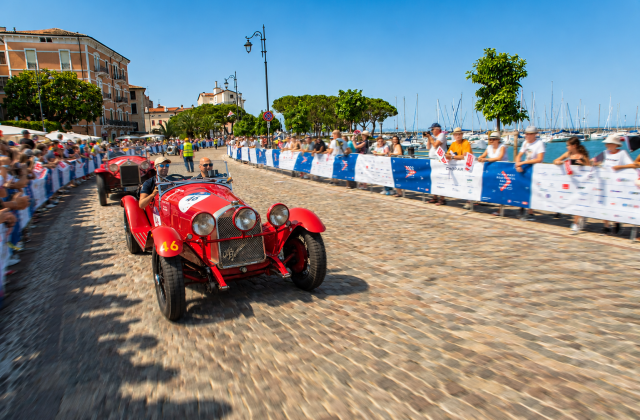 Historic red Alfa Romeo number 46 in Mille Miglia 2026 on Desenzano lakefront with crowds and sailboats