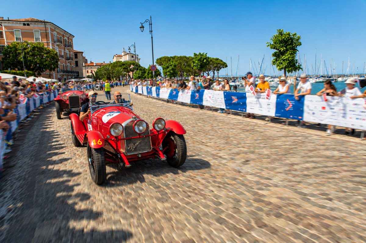 Historic red Alfa Romeo number 46 in Mille Miglia 2026 on Desenzano lakefront with crowds and sailboats