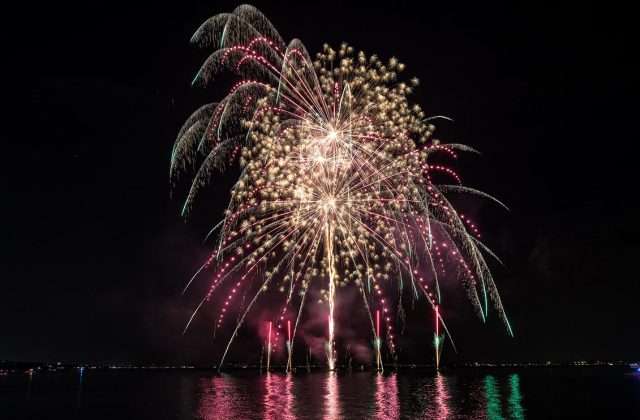 Fireworks display on Lake Garda with pink, gold and green reflections on the water