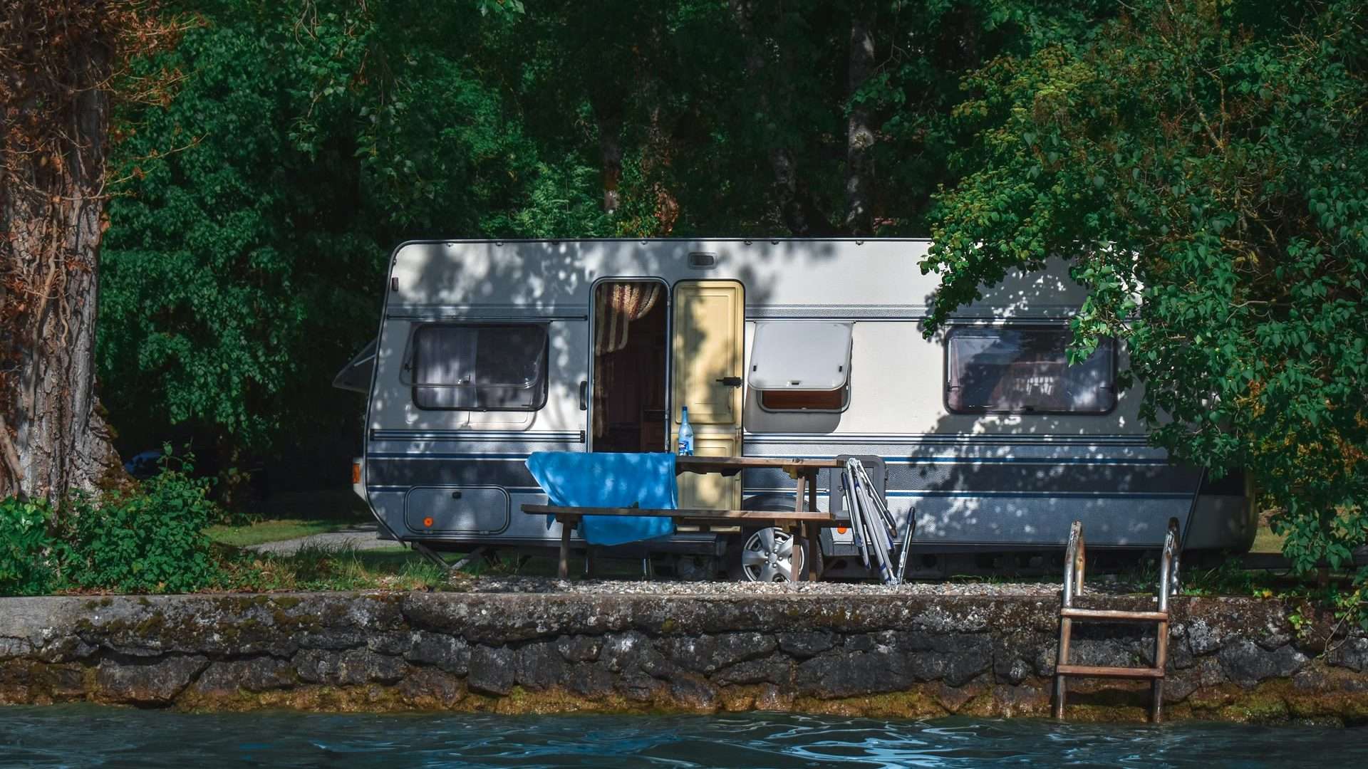 Motorhome parked on the shore of Lake Garda with a picnic table and lake access