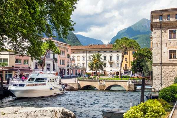 Vue du port de Riva del Garda avec bateaux, palmiers et Monte Brione en arrière-plan