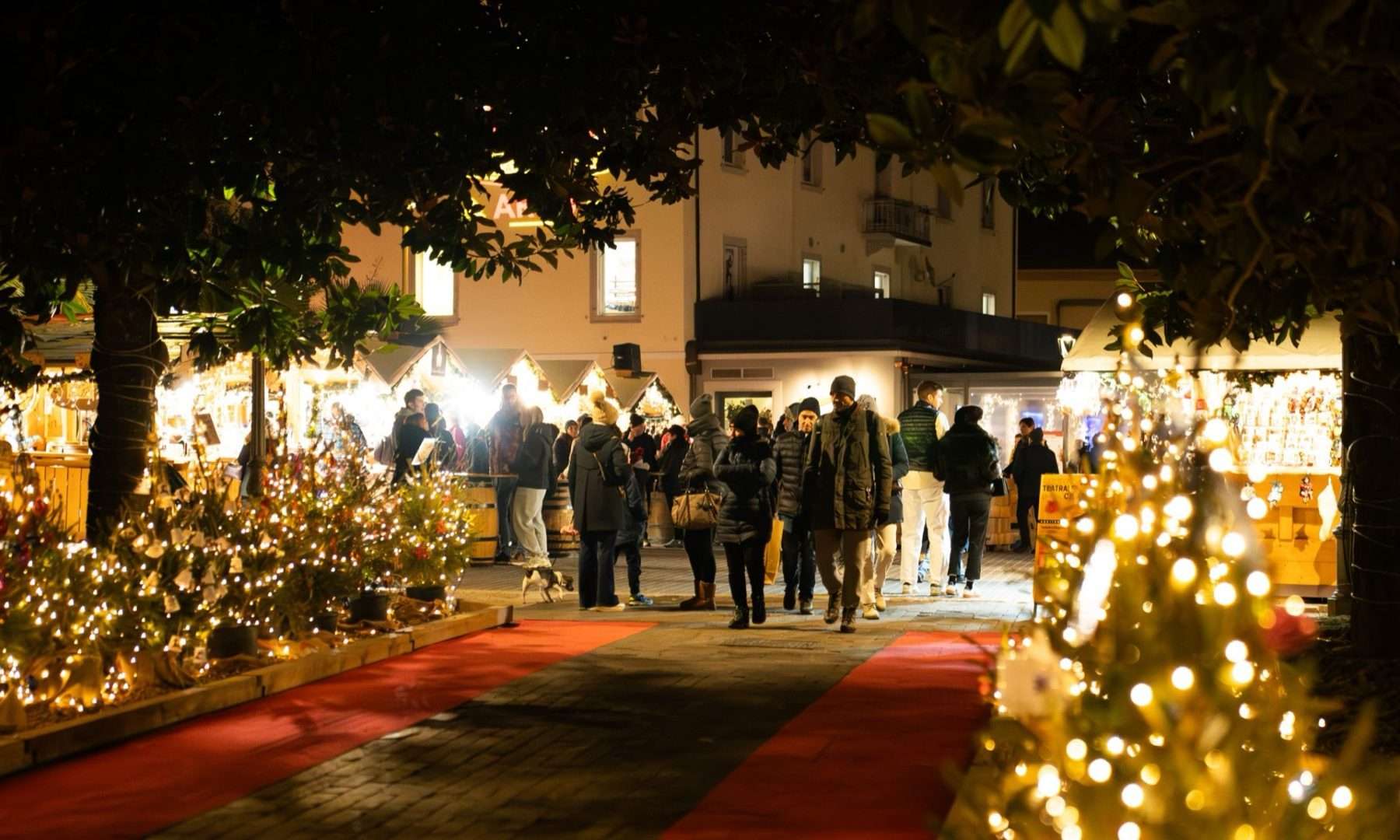 Visitatori tra le casette illuminate dei Mercatini di Natale nel centro di Arco