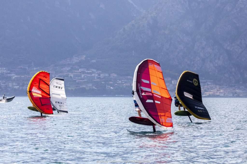 Cuatro wingfoilers en regata en el lago frente a la costa de Malcesine